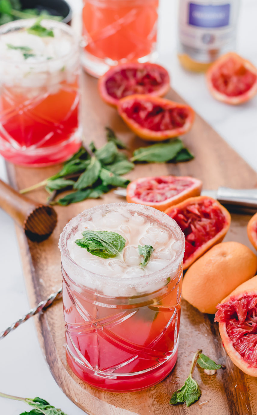 Blood Orange Kombucha Mojito on wooden tray with wooden muddler and mint leaves in a bowl of water