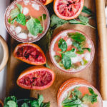 Blood Orange Kombucha Mojito on wooden tray with wooden muddler and mint leaves in a bowl of water