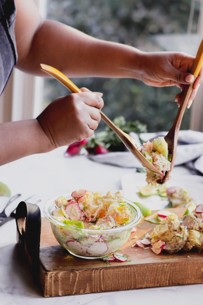 Apple Fennel Slaw, hands holding serving spoons with slaw and placing it over pork loin