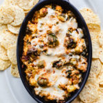 baked hot cheesy brussel sprout and bacon dip in black staub