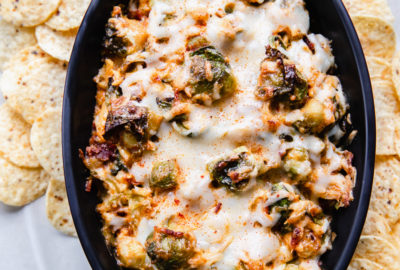baked hot cheesy brussel sprout and bacon dip in staub