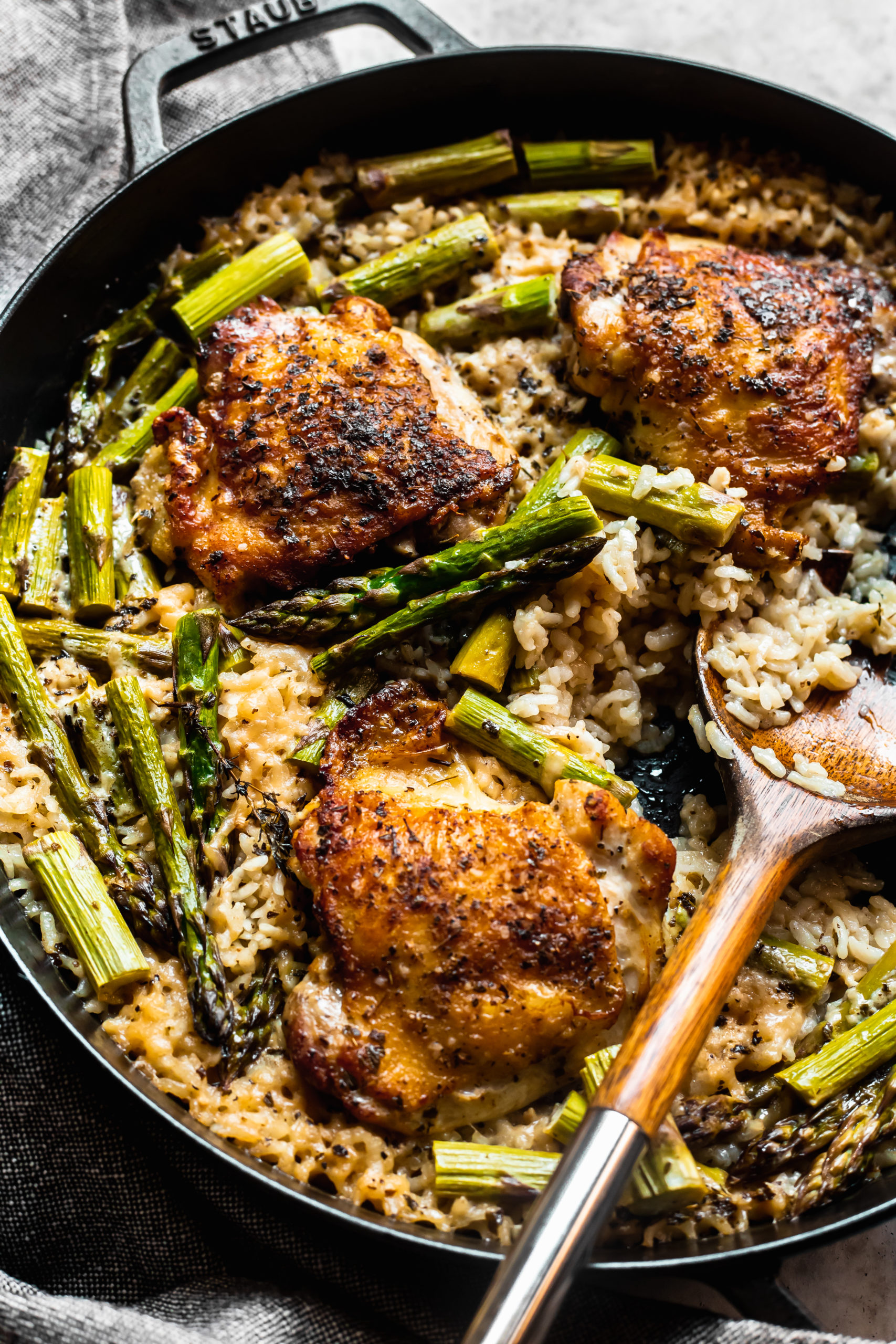 Overhead shot of baked chicken and rice in skillet with wooden spoon in skillet. 
