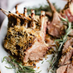 panko crusted lamb rack in a white plate with rosemary