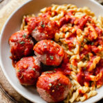 spicy Italian meatballs in a bowl with pasta and marinara sauce on top