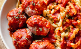 spicy Italian meatballs in a bowl with pasta and marinara sauce on top