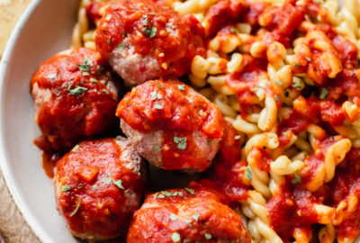 spicy Italian meatballs in a bowl with pasta and marinara sauce on top